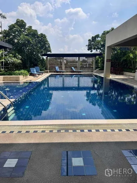 公寓 出租在Sathon, Bangkok - Supreme Ville室外游泳池，蓝色池砖、躺椅与绿化景观。