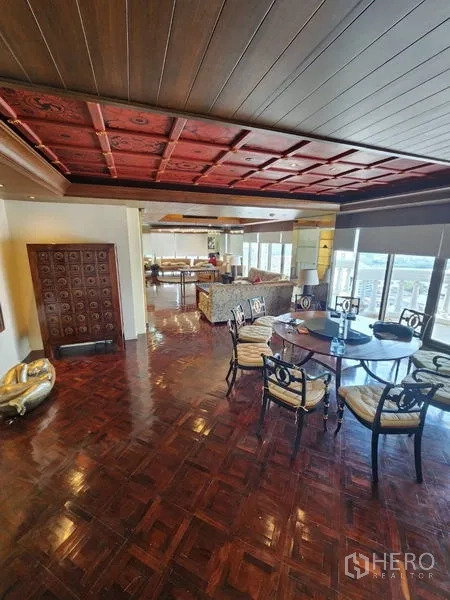 Condominium for rent in Bang Rak, Bangkok - Open-plan living and dining space with parquet floors and wall-to-wall windows.