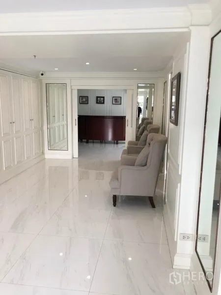 Shophouse for rent or sale in Chatuchak, Bangkok - Spacious corridor with white paneling, mirrors and armchairs.