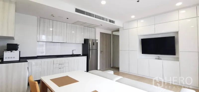 公寓 出租或出售在Watthana, Bangkok - 简洁厨房，亮面橱柜，客厅设电视特色墙。