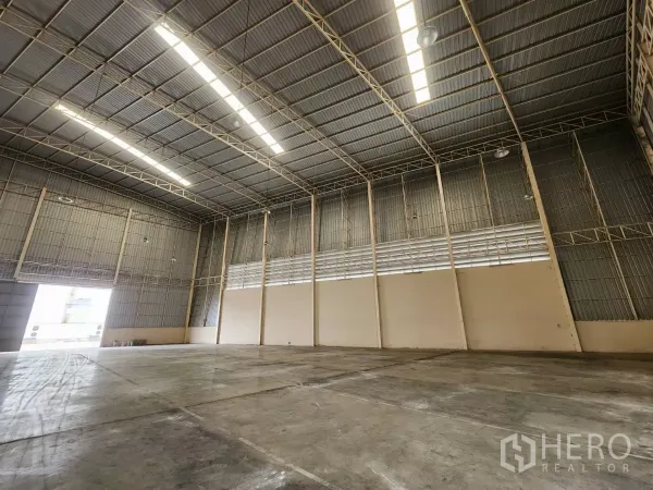 Warehouse for rent in Mueang Samut Sakhon, Samut Sakhon - High-bay warehouse with roller shutter door, ventilated wall panels, and heavy-duty concrete slab.