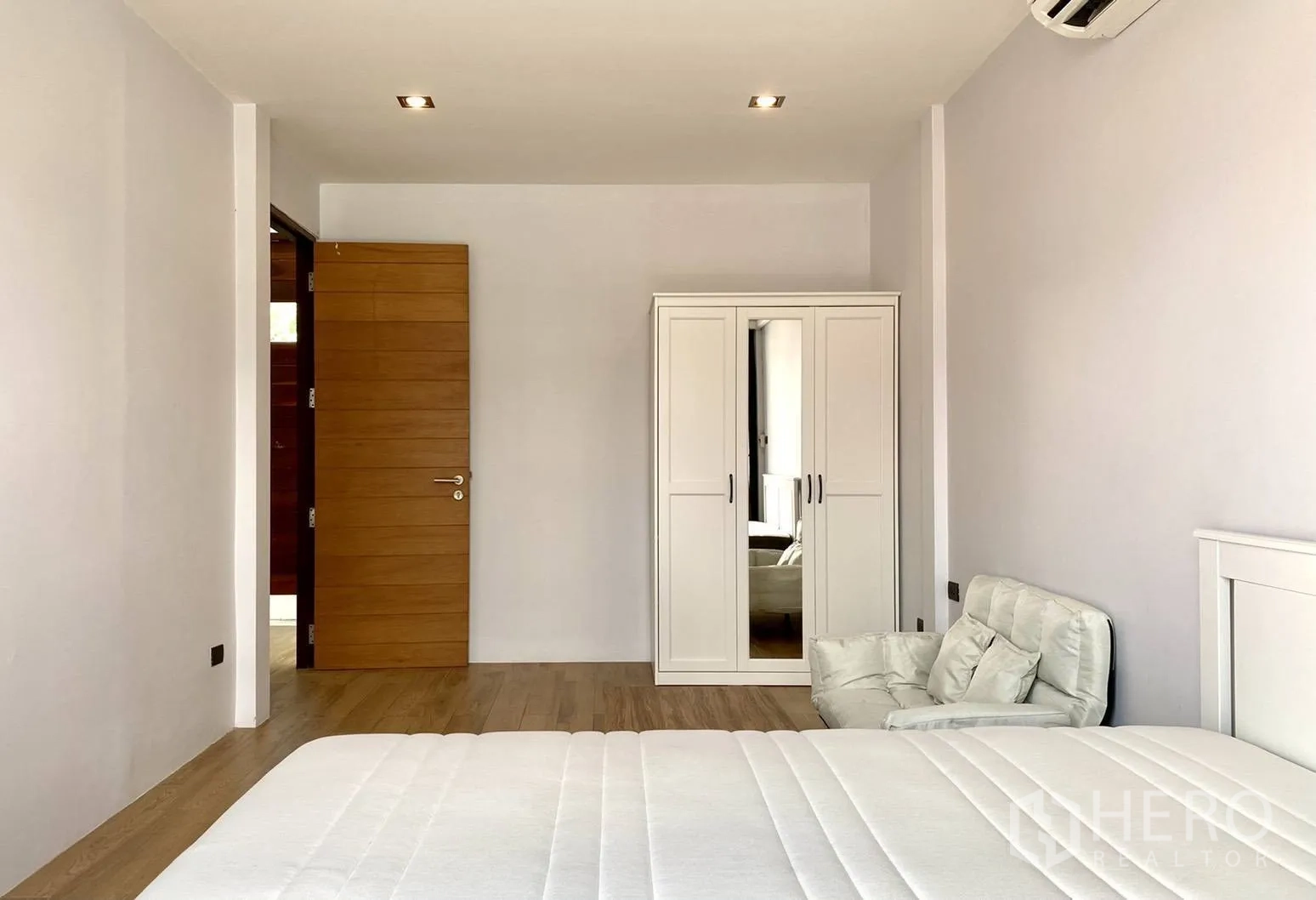 ทาวน์เฮาส์ ให้เช่าในWatthana, Bangkok - ห้องนอนพร้อมตู้เสื้อผ้าสีขาว เก้าอี้อาร์มแชร์ และประตูไม้