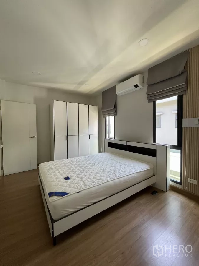 Detached House for rent in Bang Phli, Samut Prakan - Bright bedroom with black-and-white bedframe, wardrobe and air-conditioner.