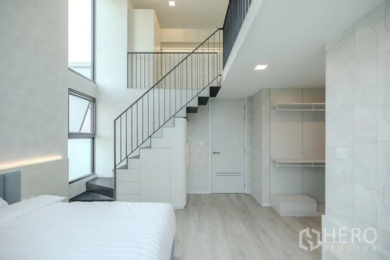 Detached House for rent in Saphan Sung, Bangkok - Loft-style bedroom showing metal staircase, open wardrobe and light wood floors.