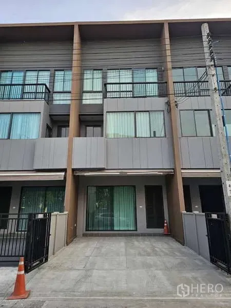 Townhouse for rent in Suan Luang, Bangkok - Townhouse exterior showing private parking area, glass doors and balconies.