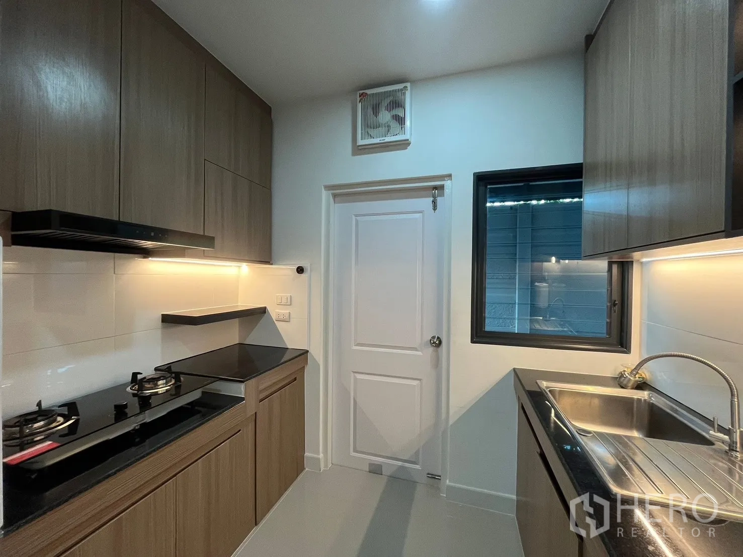 Detached House for rent in Bang Phli, Samut Prakan - Fitted kitchen with wood cabinets, gas hob, black countertops and stainless-steel sink.