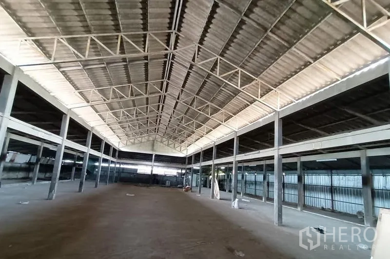 货栈 出租在Saphan Sung, Bangkok - 宽敞仓库内部，高耸人字形屋顶与钢桁架，开放式地面空间。