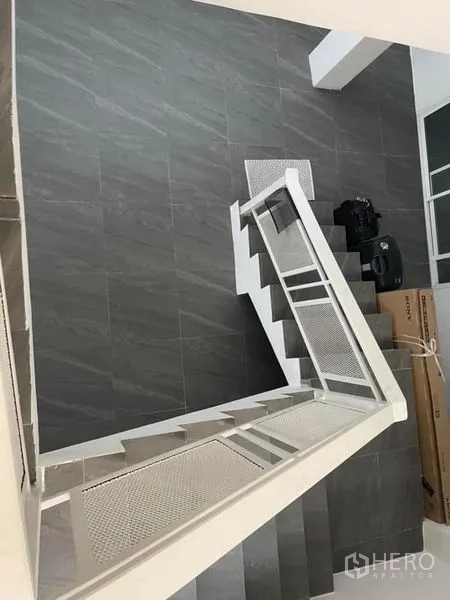 Townhouse for sale in Din Daeng, Bangkok - Open stairwell with white metal railing and grey tiled flooring inside the townhouse.