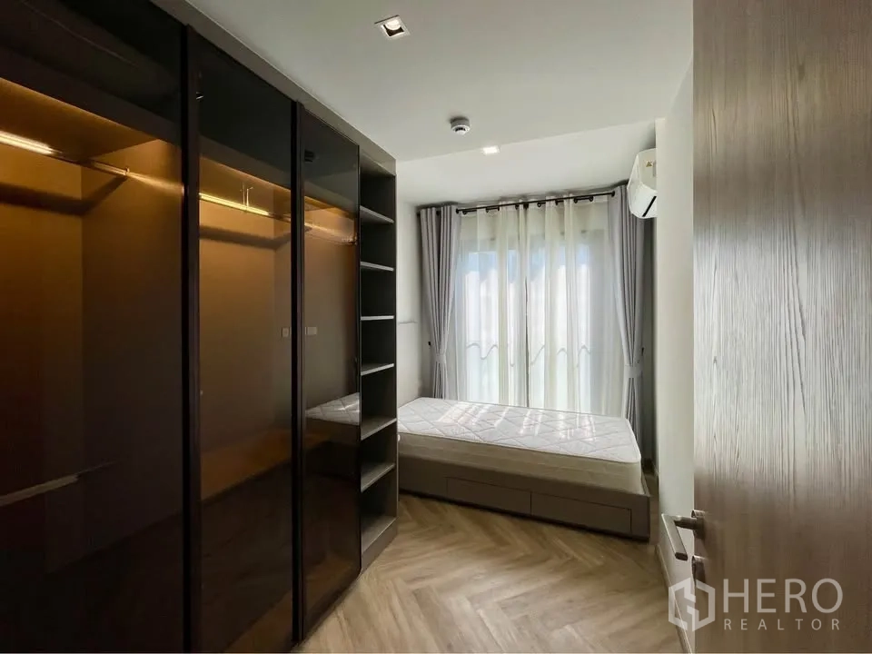 公寓 for rent in Watthana, Bangkok - 卧室配玻璃门衣柜、床、纱帘与人字形木地板。