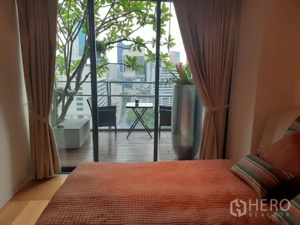 Condominium for rent or sale in Sathon, Bangkok - Bedroom opening to a balcony with city view, sliding glass doors and a compact bistro set.