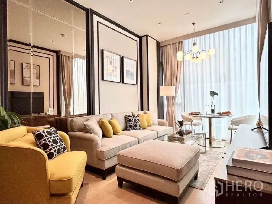Condominium for rent in Pathum Wan, Bangkok - High-ceiling living room with chandelier, sheer curtains and a dining nook.