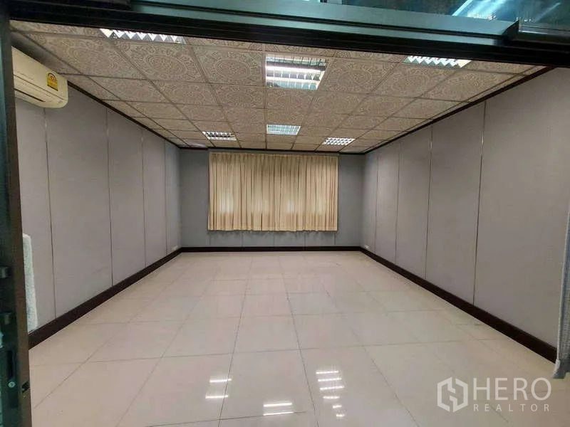 Warehouse for rent in Min Buri, Bangkok - Air-conditioned office room with tiled floors, drop ceiling and curtains.