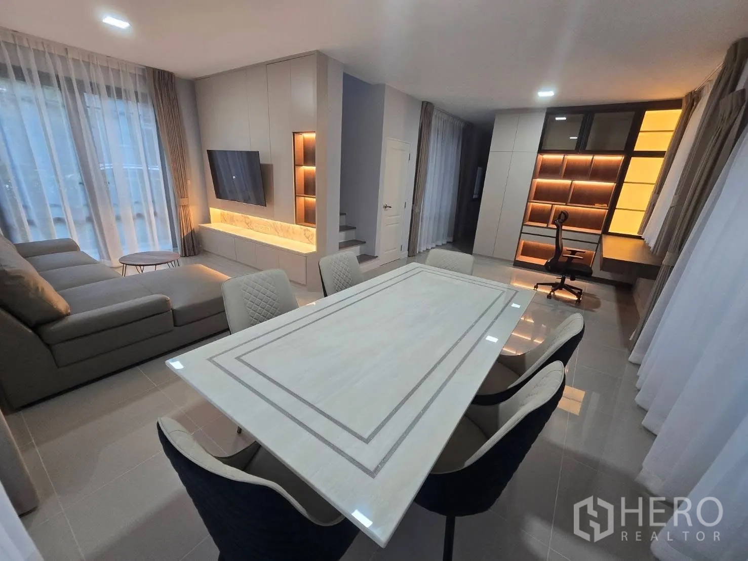 Semi-detached House for rent in Bang Phli, Samut Prakan - Open-plan living and dining area with sectional sofa, TV wall, and six-seat table.
