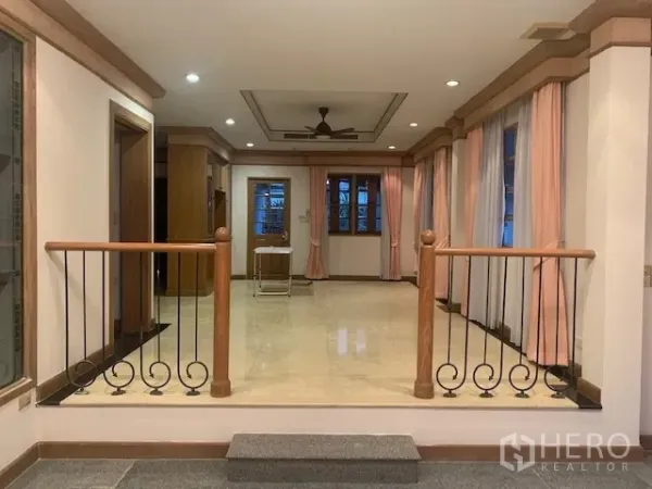 独立式住宅 出租在Khan Na Yao, Bangkok - 抬高入口玄关，抛光瓷砖地面，铁艺木扶手、吊扇与窗帘。