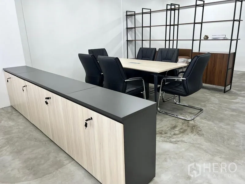 办公空间 出租在Sathon, Bangkok - 会议桌与黑色皮椅，旁设低柜储物空间。