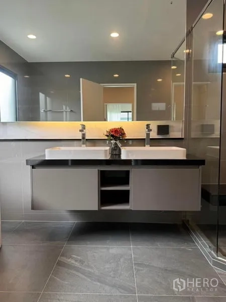 Detached House for rent or sale in Bang Kapi, Bangkok - Modern bathroom with double vanity, mirror and glass shower.