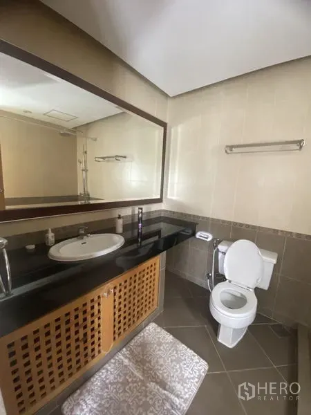 Condominium for rent - Tiled bathroom with long granite countertop, large framed mirror and toilet for a clean, practical layout.