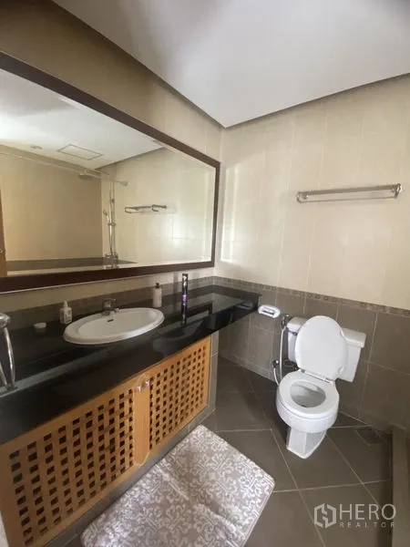 Condominium for rent - Tiled bathroom with long granite countertop, large framed mirror and toilet for a clean, practical layout.