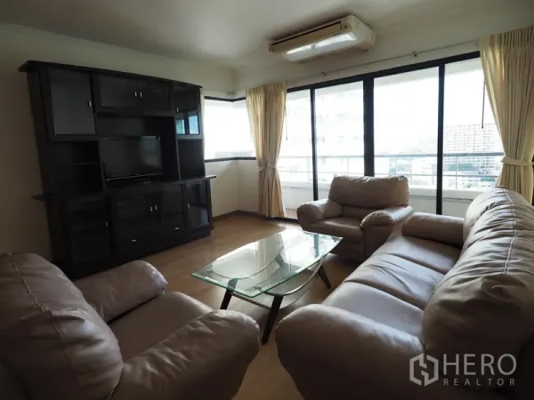 公寓 出租在Sathon, Bangkok - 转角客厅配大窗、皮质沙发与电视柜，可眺望城市景观的沙吞公寓。