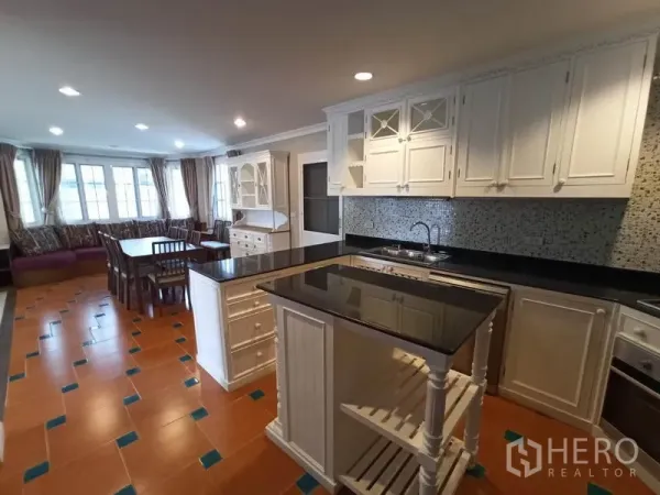 独立式住宅 出租在Mueang Samut Prakan, Samut Prakan - 整体厨房，白色橱柜、黑色花岗岩台面、中岛与马赛克墙面。