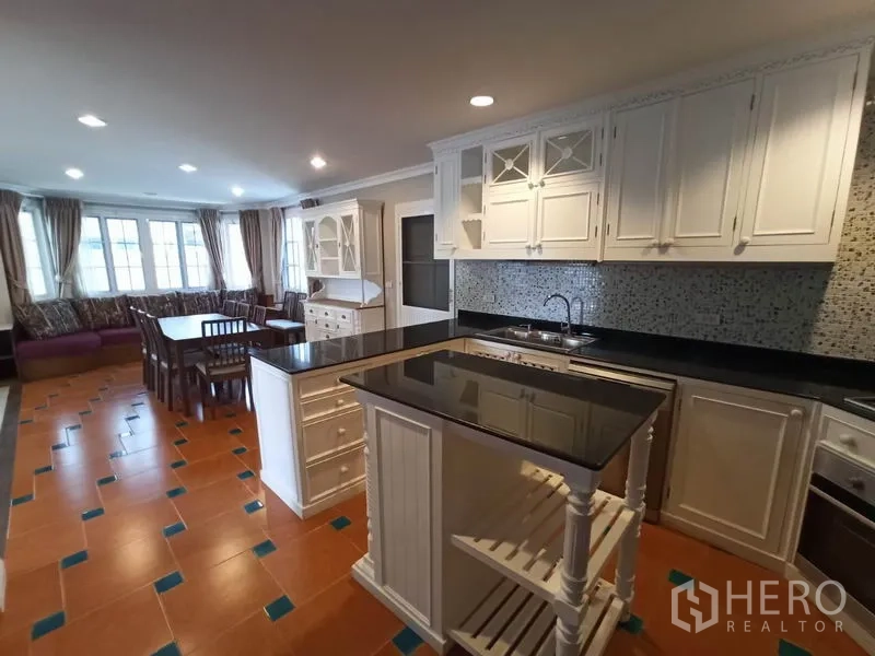 独立式住宅 出租在Mueang Samut Prakan, Samut Prakan - 整体厨房，白色橱柜、黑色花岗岩台面、中岛与马赛克墙面。