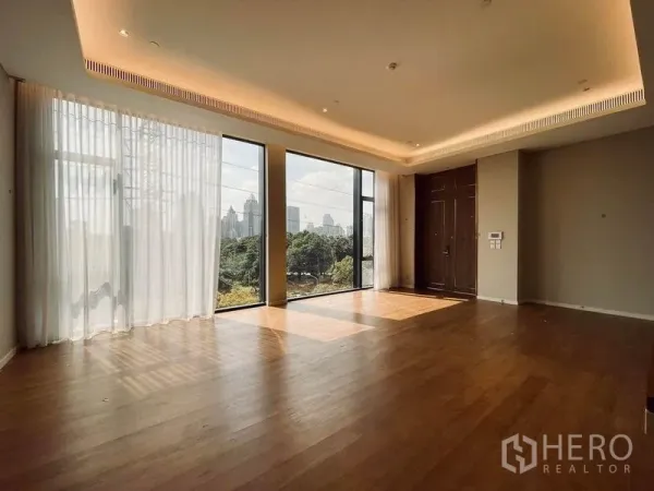 คอนโด ขายในPathum Wan, Bangkok - ห้องนั่งเล่นกว้าง หน้าต่างเต็มผนัง ไฟซ่อน ฝั่งวิวสวนและสกายไลน์เมือง