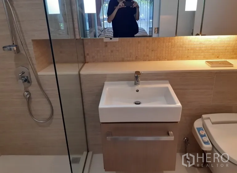 คอนโด ให้เช่าในWatthana, Bangkok - มุมอ่างล้างหน้าพร้อมฝักบัวกระจกและโถสุขภัณฑ์บิเดต์ โทนสีอบอุ่น
