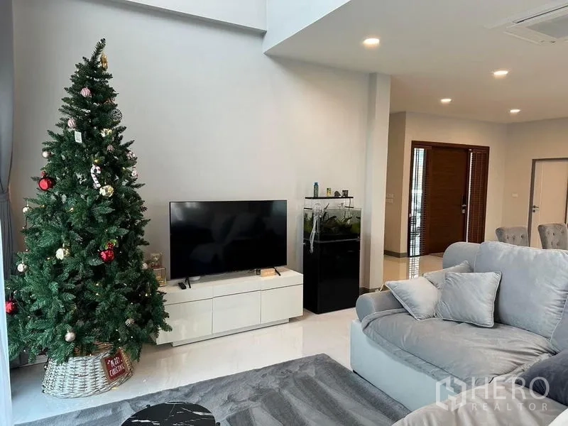 独立式住宅 出租在Bang Phli, Samut Prakan - 客厅一角，电视柜、鱼缸与柔软沙发，通往餐区的动线。