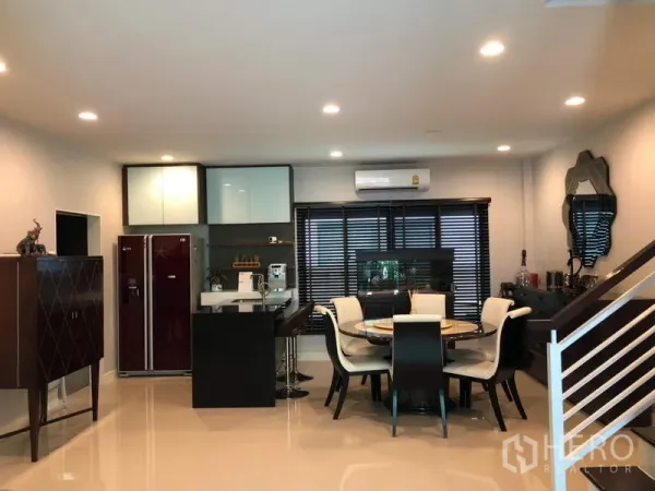 Detached House for rent or sale in Bang Kapi, Bangkok - Open-plan kitchen and dining area with island counter, modern lighting and nearby staircase.