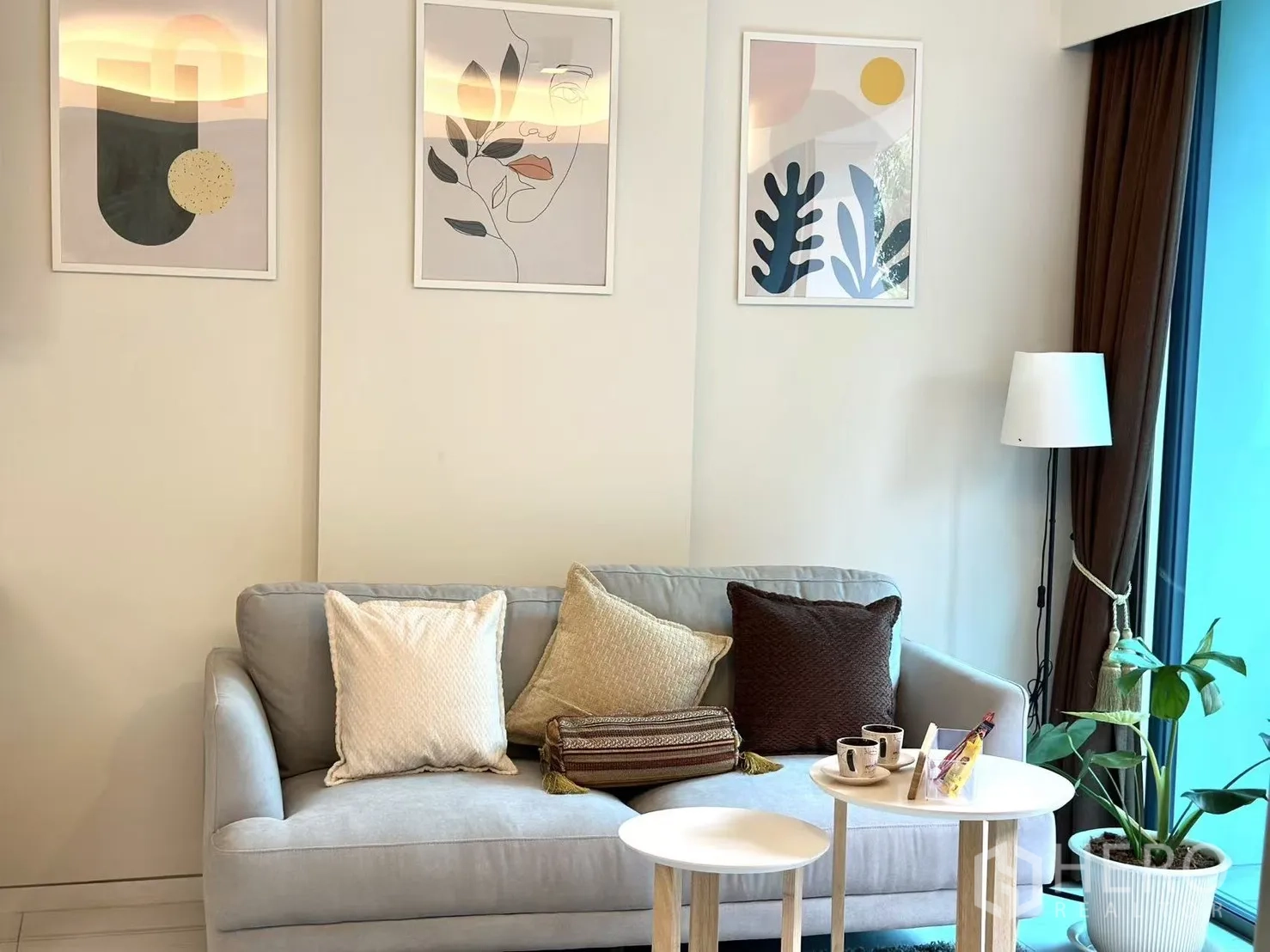 คอนโด ขายในWatthana, Bangkok - ห้องนั่งเล่นอบอุ่น โซฟาสีเทา งานศิลป์ติดผนัง และโคมไฟตั้งพื้น