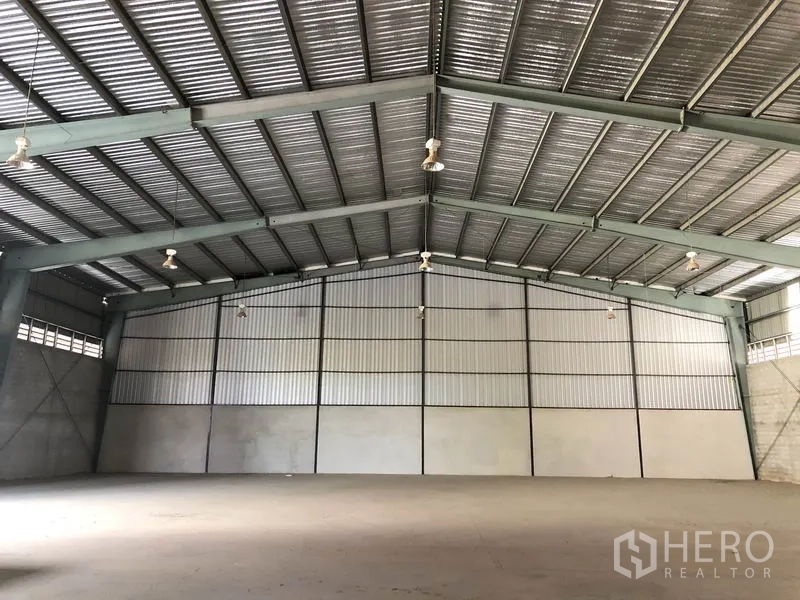 Warehouse for rent in Sai Noi, Nonthaburi - Spacious warehouse interior with clear-span steel trusses, high gabled roof and smooth concrete floor.