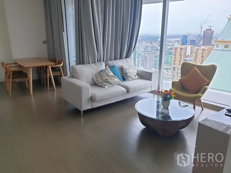 คอนโด ให้เช่าในPathum Wan, Bangkok - โซนพักผ่อนมีโซฟา โต๊ะกลางทรงกลม ชุดทานอาหาร และหน้าต่างสูงจรดเพดานมุมมองเมืองพาโนรามา