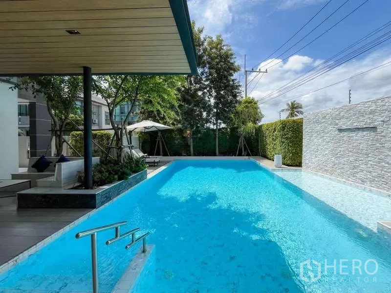 Detached House for sale in Bang Lamung, Chon Buri - Long lap‑style swimming pool beside landscaped garden and privacy walls.