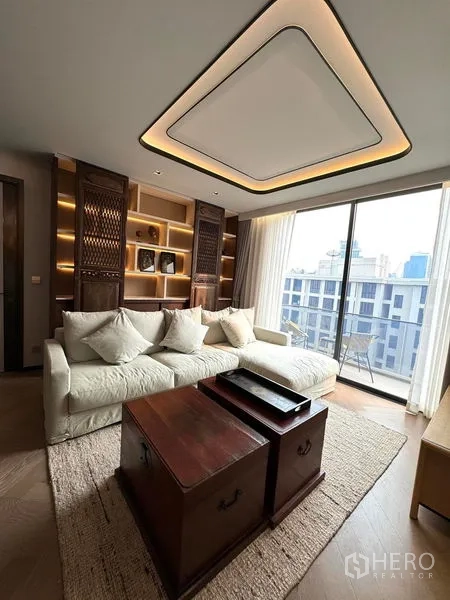 Condominium for rent in Watthana, Bangkok - Living area with custom built-in shelving and balcony access.