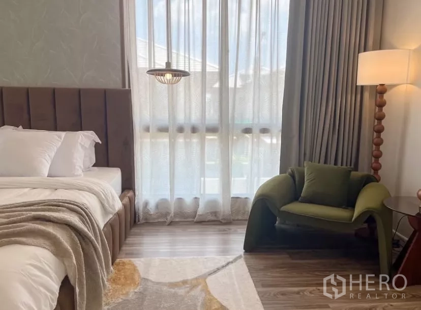 Detached House for rent or sale in Bang Kapi, Bangkok - Bedroom reading nook featuring a designer green armchair by a tall window.