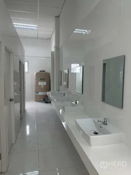 Factory for rent in Khlong Luang, Pathum Thani - Clean staff washroom corridor with multiple basins and mirrors in the factory building.
