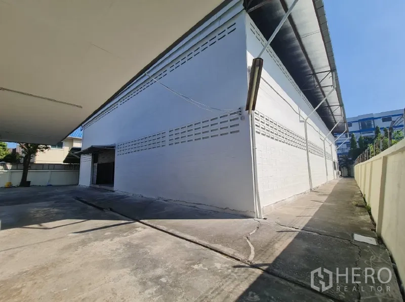 Warehouse for rent in Khlong Toei, Bangkok - Side walkway along the warehouse wall with ventilation blocks and eaves.