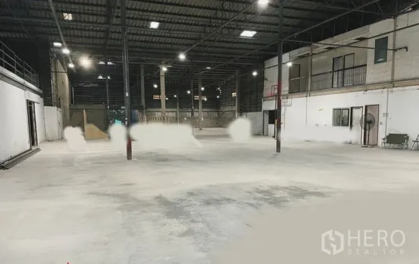 Warehouse for rent or sale in Mueang Nonthaburi, Nonthaburi - Spacious warehouse interior with high steel truss roof, concrete floor, and mezzanine offices along one wall.