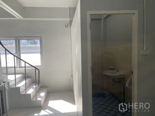 店屋 出租在Bang Na, Bangkok - 带窗采光的楼梯间，旁边为瓷砖卫生间入口