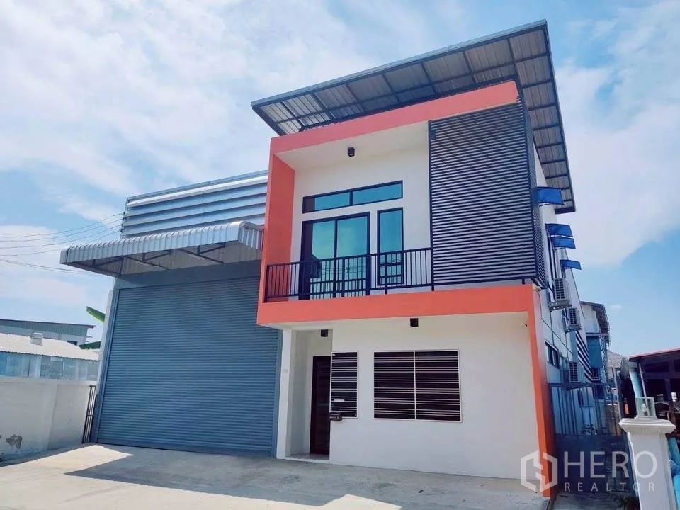 Warehouse for rent in Lam Luk Ka, Pathum Thani - Corner view of warehouse with orange trim, louvered panels and side AC units.