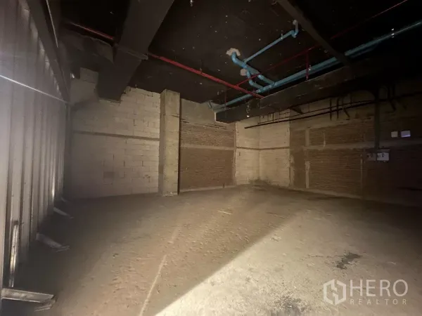 零售空间 出租 - 空置商铺，砖块与砌块墙，高挑黑色天花配有红蓝管线与风管。