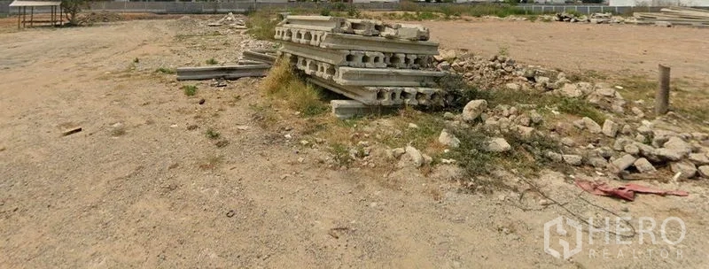 Land for sale in Lam Luk Ka, Pathum Thani - Leveled vacant land with compacted soil and stacked precast concrete beside boundary fencing in Lam Luk Ka, Pathum Thani.