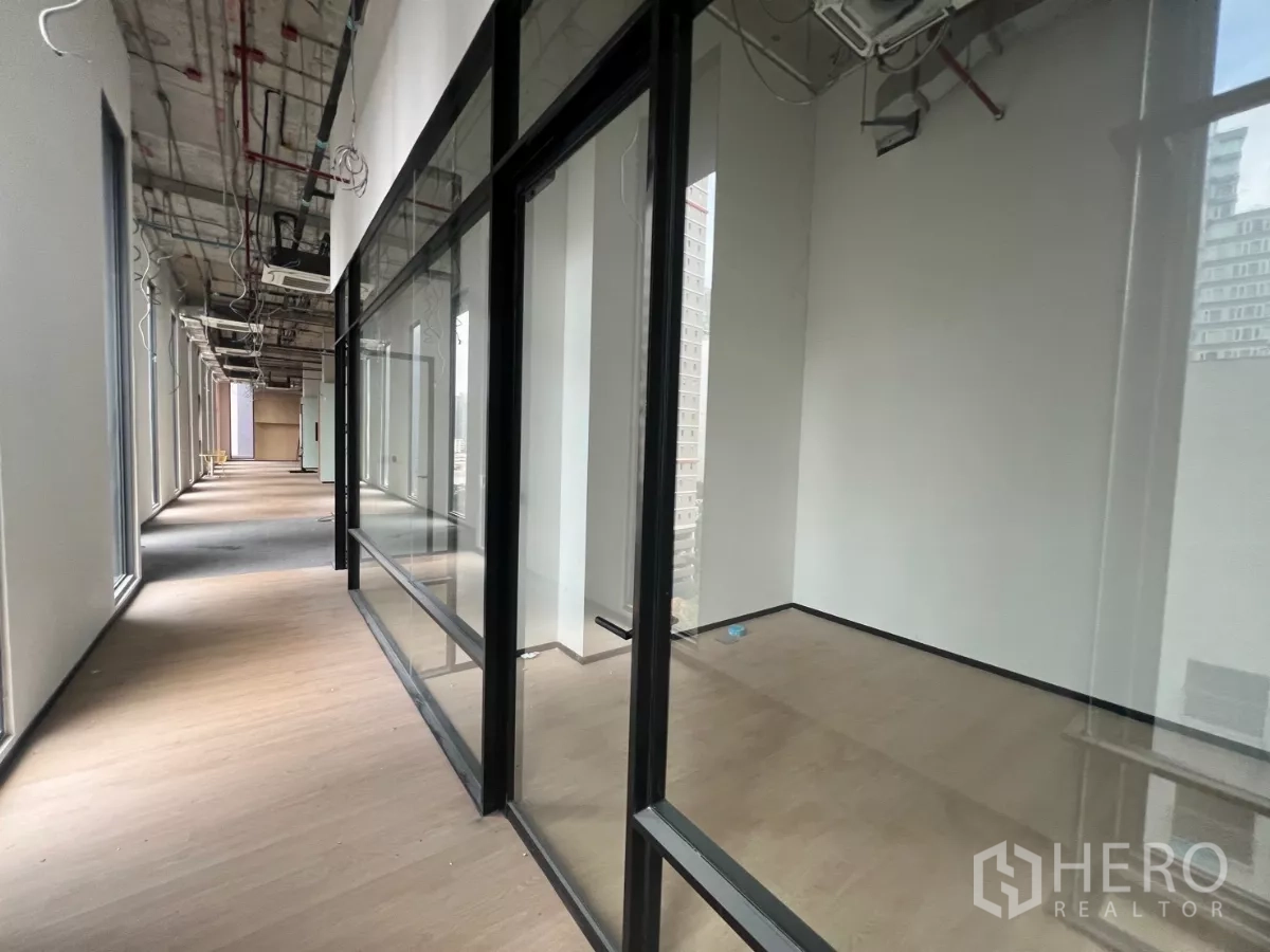 零售空间 出租 - 玻璃门面沿宽敞走廊展开，木质地板与外露天花的零售区。