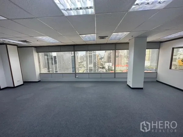 办公空间 出租在Pathum Wan, Bangkok - 开放式办公室，地毯地面、方格吊顶照明，大窗眺望曼谷天际线。