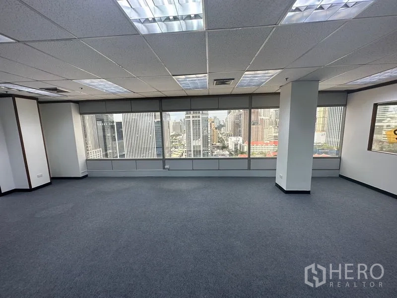 办公空间 出租在Pathum Wan, Bangkok - 开放式办公室，地毯地面、方格吊顶照明，大窗眺望曼谷天际线。