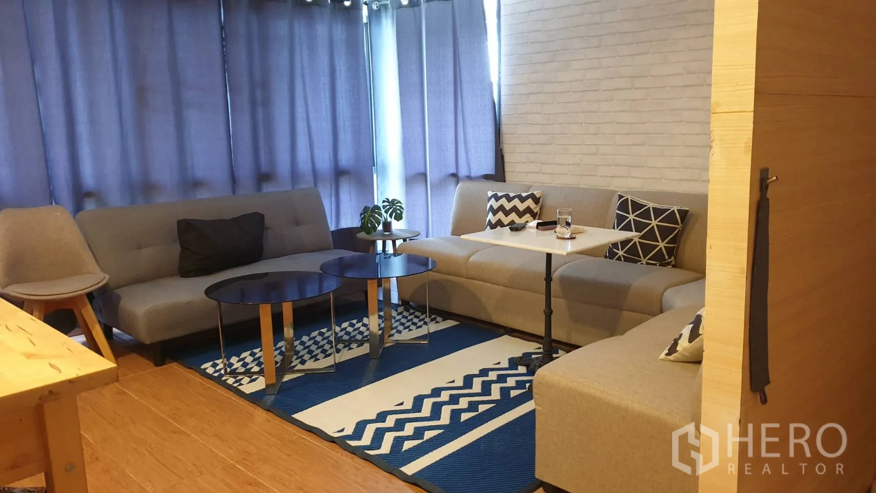 独栋房屋 for rent in Watthana, Bangkok - 温馨客厅配灰色沙发、圆形茶几、图案地毯和窗帘。