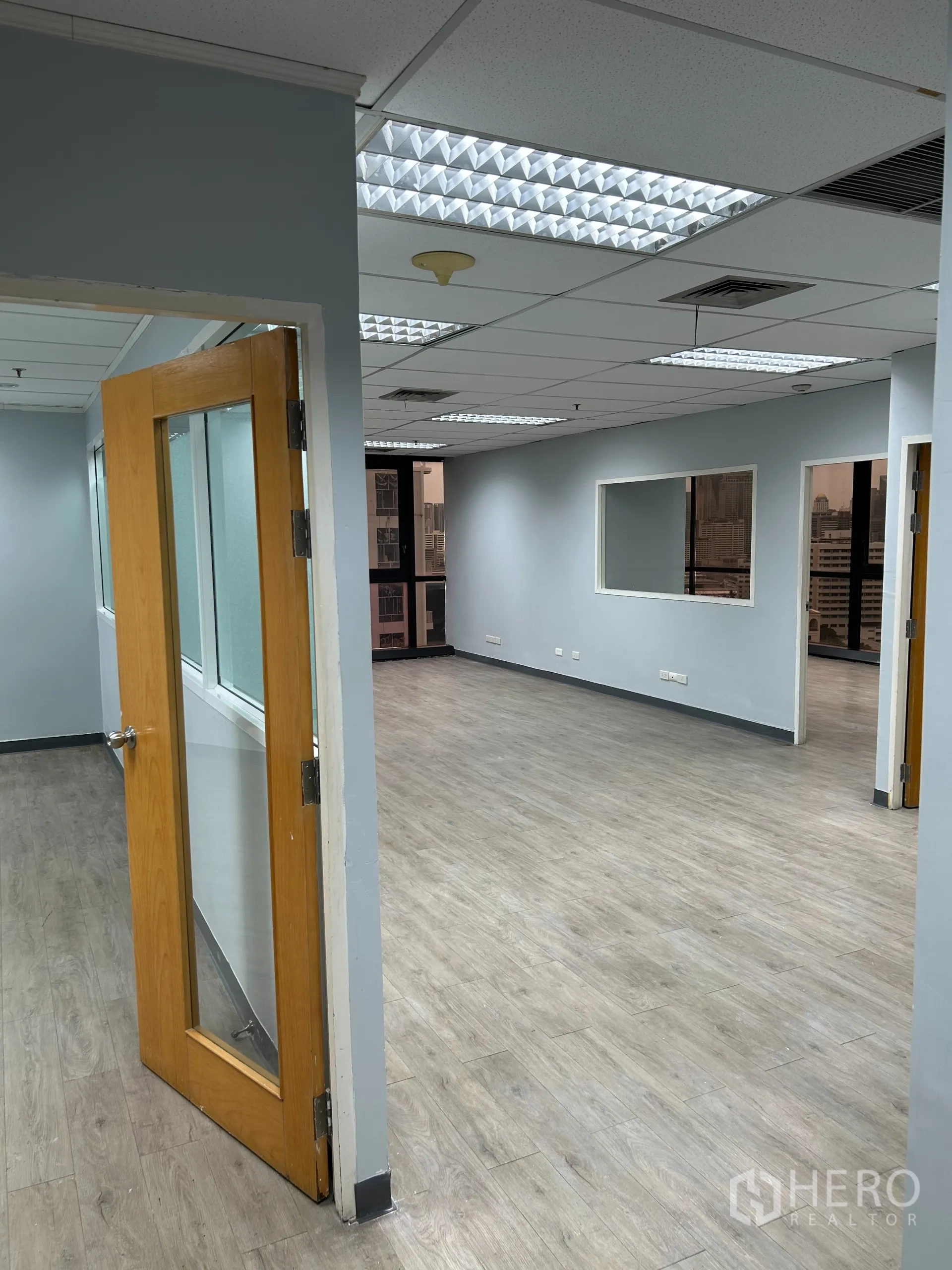 办公空间 出租在Khlong Toei, Bangkok - 从走道望向主办公区，木门、木纹地板与大窗采光。