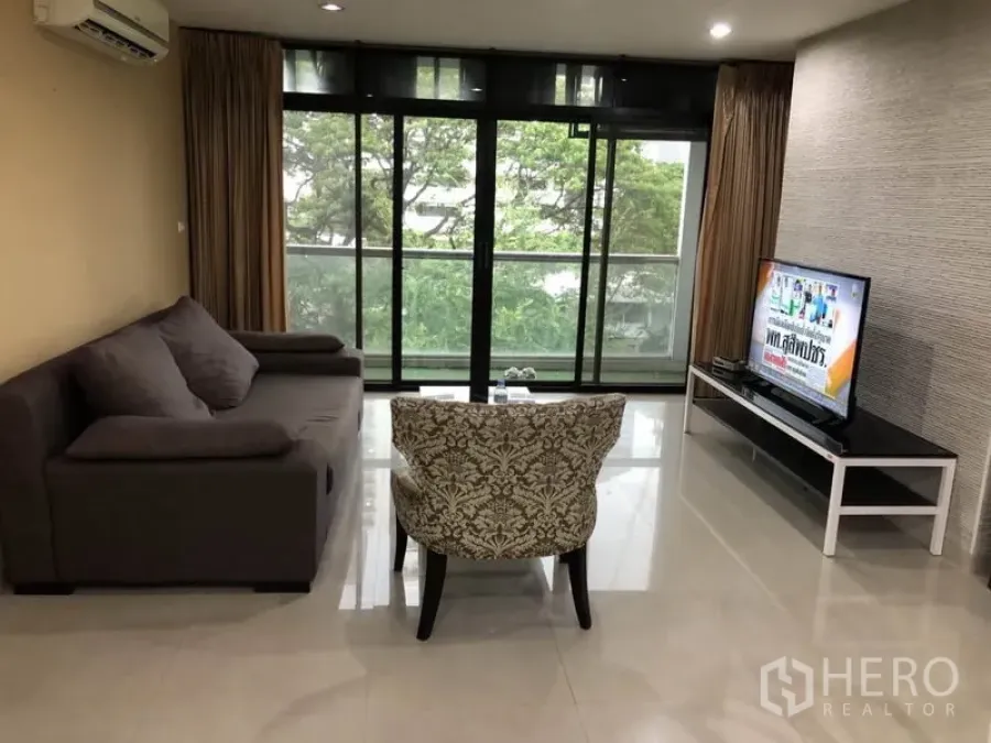 คอนโด ให้เช่าในWatthana, Bangkok - ห้องนั่งเล่นคอนโดในเขตวัฒนา พร้อมโซฟา ทีวี และระเบียงวิวต้นไม้