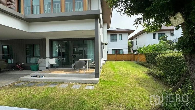 Detached House for rent in Prawet, Bangkok - Side garden with green lawn beside covered terrace and sliding glass doors.