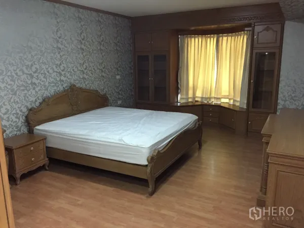 Condominium for rent in Watthana, Bangkok - Master bedroom with wooden bed, patterned wallpaper, bay window cabinetry, and extensive built-in storage.